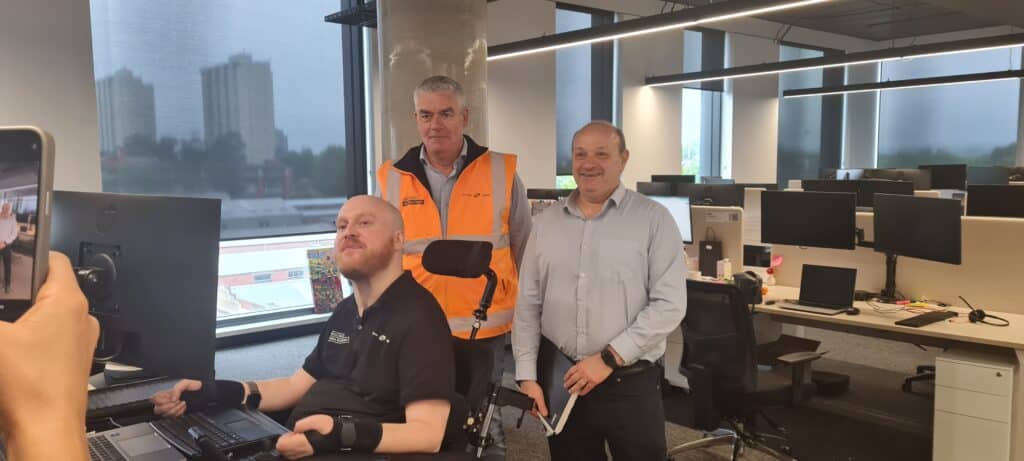 Three serious lookng men in an office setting pose for the camera.