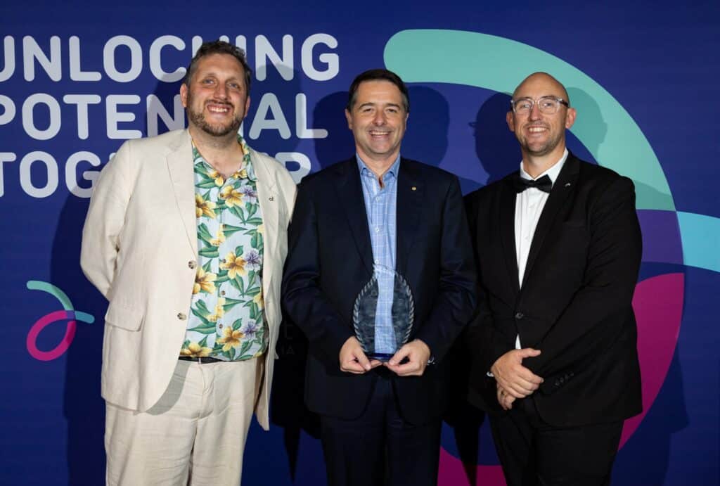 DEA Hall of Fame inductee Professor Alastair McEwin AM is holding his trophy and standing between DEA CEO Peter Bacon (left) and DEA Chair Mat McIntyre (right)