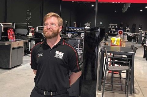 Simon, a fair-haired, bearded man in his 30s, stands proudly in a Barbecues Galore showroom.