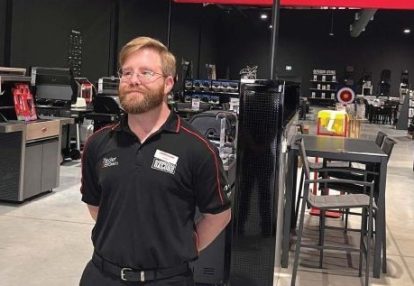 Simon, a fair-haired, bearded man in his 30s, stands proudly in a Barbecues Galore showroom.