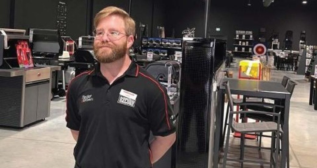 Simon, a fair-haired, bearded man in his 30s, stands proudly in a Barbecues Galore showroom.