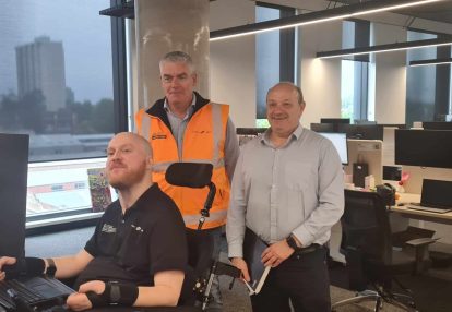 Three serious lookng men in an office setting pose for the camera.