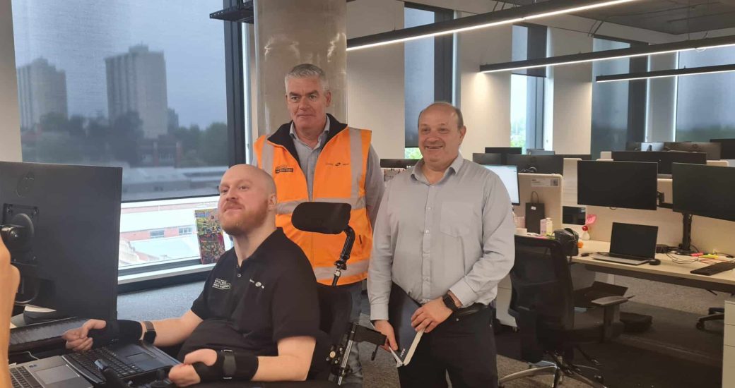 Three serious lookng men in an office setting pose for the camera.